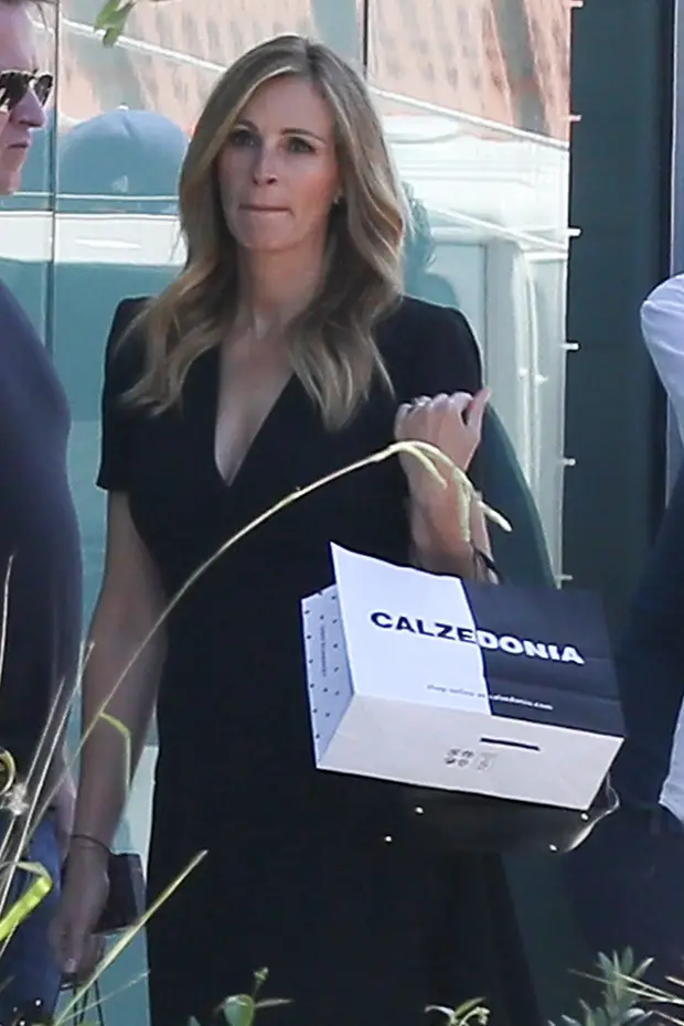 Julia Roberts is spotted filming for Italian fashion brand, Calzedonia. The 49 year old beauty and actress glows while on set as she poses as she walks out of the store with many bags. She sports a little black dress, stockings, and oxfords as she does a few takes with the crew before returning to her trailer after a long day of filming. 