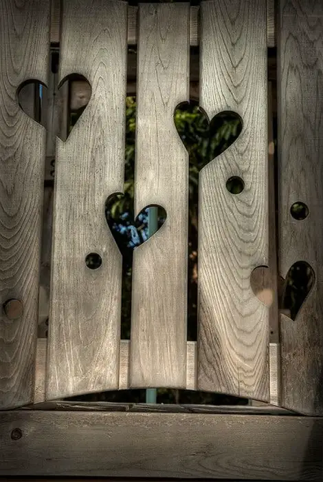 Cerca de madera con corazones tallados.