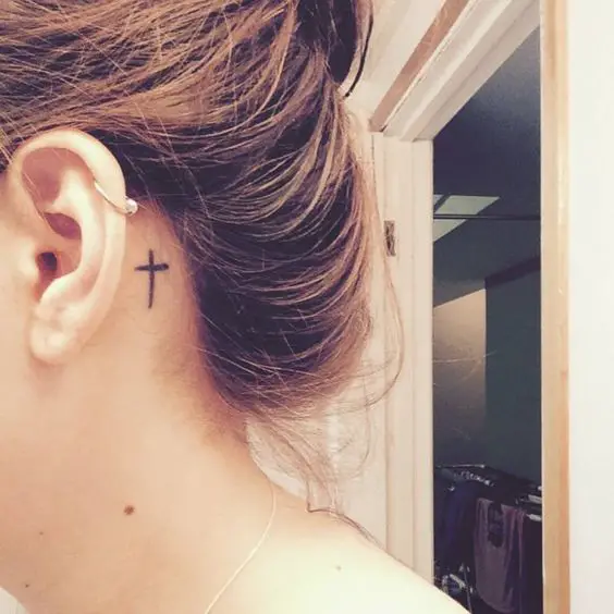 Behind the ear tattoo of a christian cross on Britt.: 