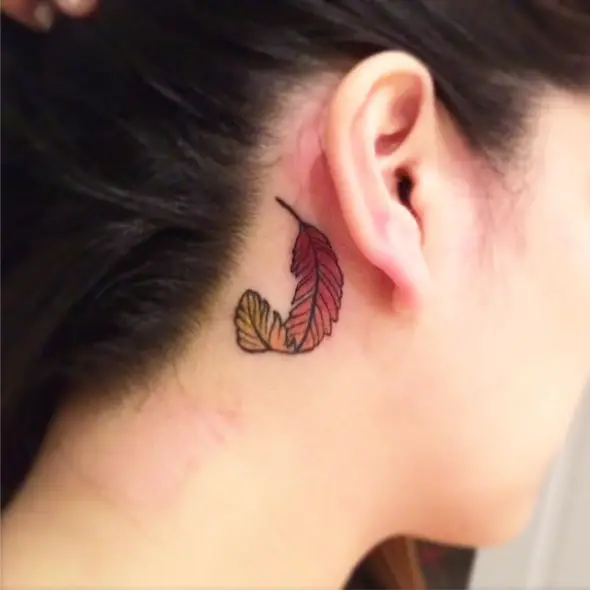 pequeño tatuaje pluma de fénix detrás de la oreja
