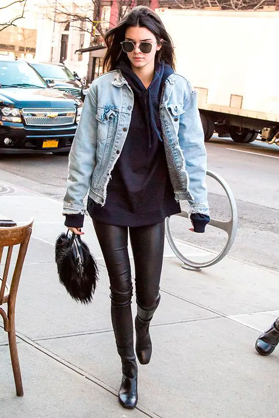 Kendall Jenner usa jaqueta jeans com moletom com calça de couro e botas pretas: 