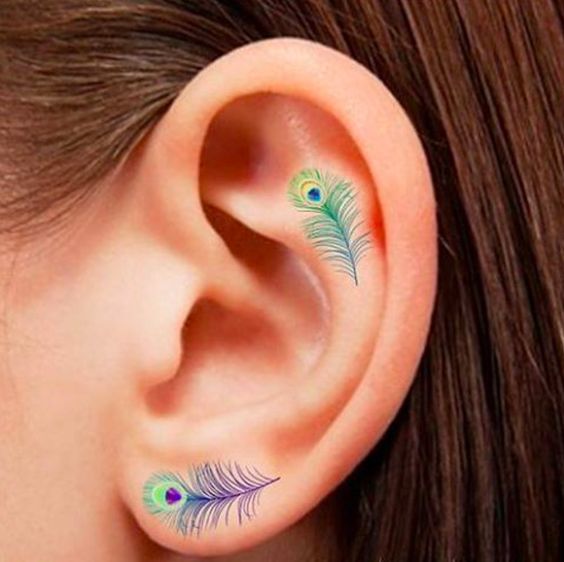 Unas sutiles plumas de pavo real llenas de colores. | 19 Tatuajes lindísimos que se verán perfectos en tus orejas: 
