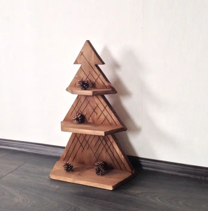 Un pequeño refugio de madera en forma de un árbol con tres estantes, en el que puede organizar hermosas figuras de Año Nuevo o colgar una guirnalda de luces.