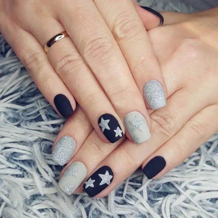 Uñas decoradas con estrellas doradas sobre fondo blanco.